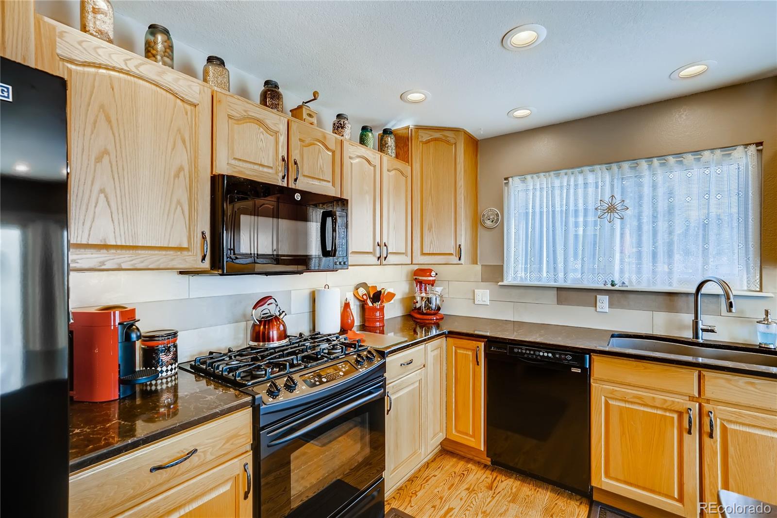 1376 Northridge Road Highlands Ranch, CO 80126 - Photo 8 of 28 a kitchen with stainless steel appliances granite countertop a stove a sink and a microwave