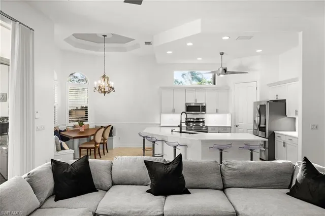 a living room with furniture kitchen view and a chandelier