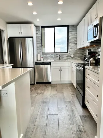 a kitchen with stainless steel appliances granite countertop a refrigerator and a stove top oven
