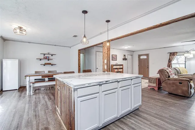 a open kitchen with stainless steel appliances granite countertop a kitchen island a stove a refrigerator a sink a dining table and chairs with wooden floor