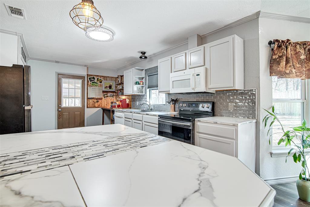 2521 Timber Road Burleson, TX 76028 - Photo 21 of 34 a kitchen with stainless steel appliances kitchen island granite countertop a refrigerator stove microwave and cabinets