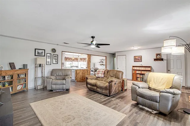 a kitchen with stainless steel appliances kitchen island granite countertop a refrigerator a stove a microwave oven a dining table and chairs with wooden floor