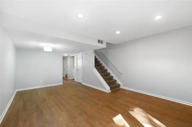 a view of an empty room with wooden floor and stairs
