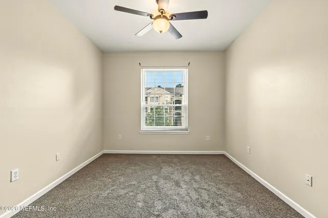 an empty room with a window and a fan