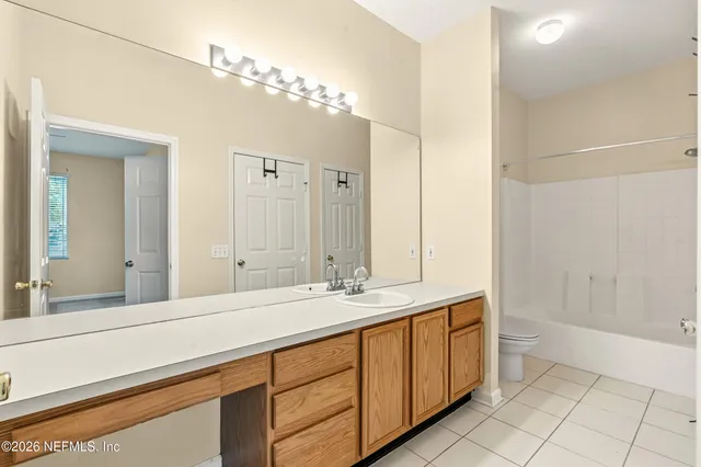 a spacious bathroom with a double vanity sink a large mirror and a shower