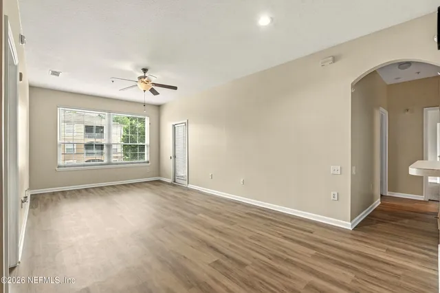 a view of an empty room with a window and wooden floor