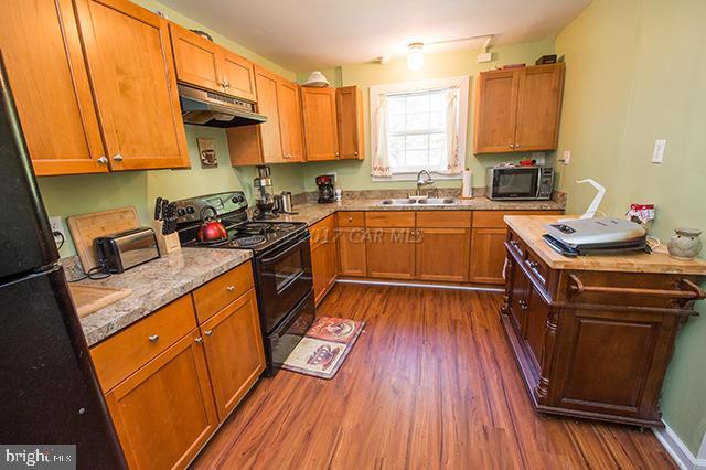 31403 Melson Road Delmar, MD 21875 - Photo 9 of 38 a kitchen with stainless steel appliances a stove a sink dishwasher and a refrigerator with wooden floor