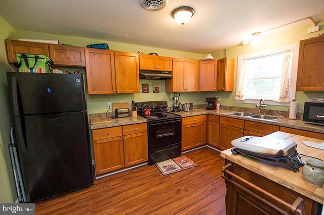 31403 Melson Road Delmar, MD 21875 - Photo 10 of 38 a kitchen with a refrigerator wooden floor a stove a sink and cabinets