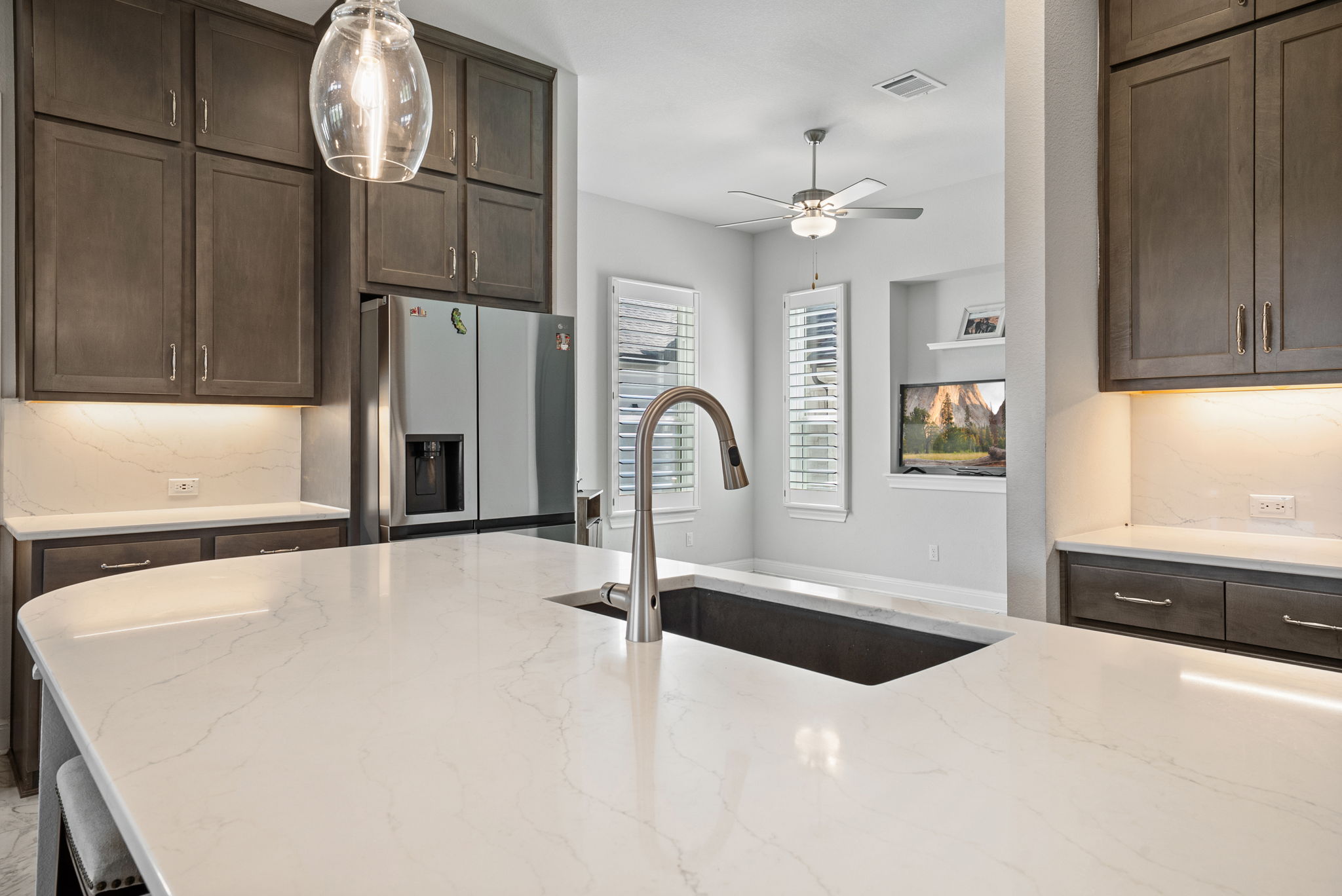 2132 Novara Trail Leander, TX 78641 - Photo 28 of 40 Kitchen with dark wood finish cabinets, backsplash, stainless steel refrigerator with ice dispenser, and light stone counters
