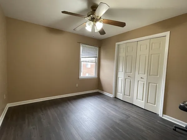 an empty room with wooden floor fan and windows