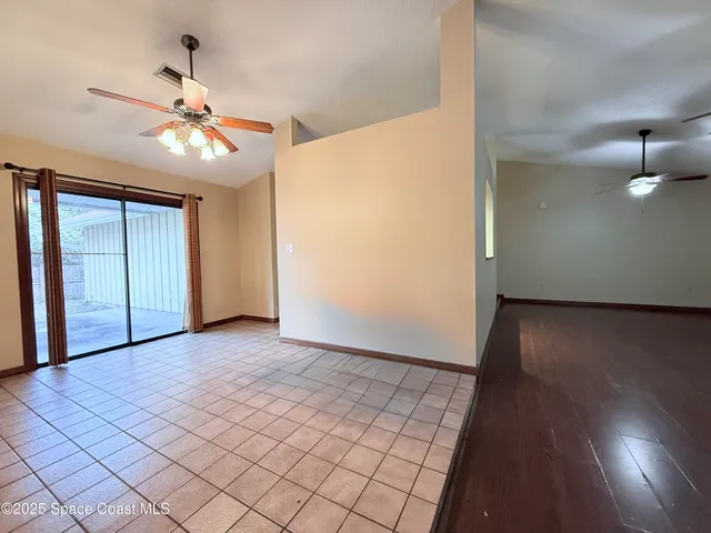 an empty room with wooden floor chandelier fan and windows