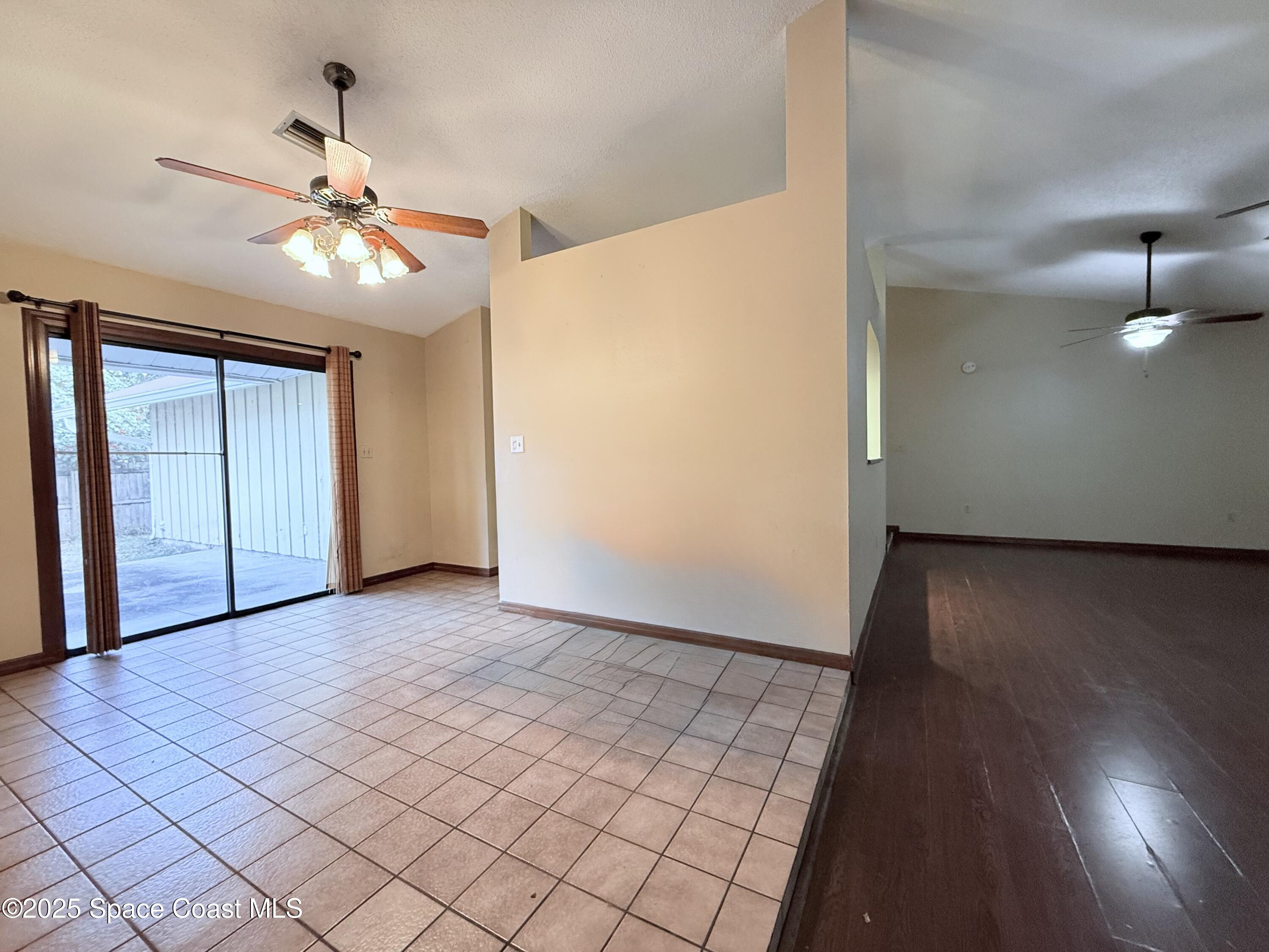 6180 Balboa Street Cocoa, FL 32927 - Photo 12 of 44 an empty room with wooden floor chandelier fan and windows