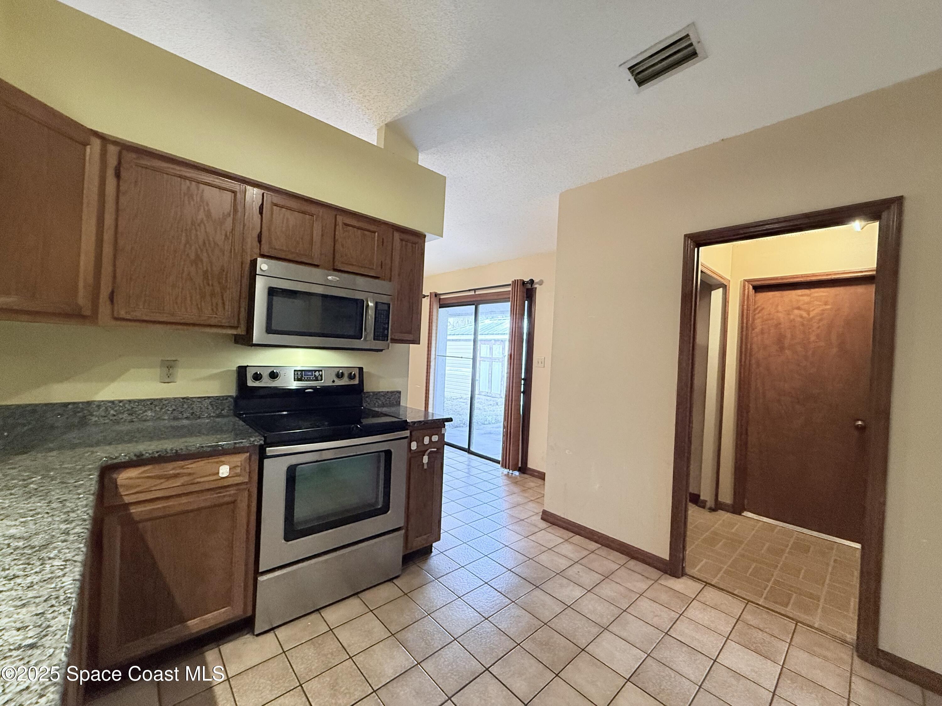 6180 Balboa Street Cocoa, FL 32927 - Photo 14 of 44 a kitchen with stainless steel appliances granite countertop a stove a microwave and a sink