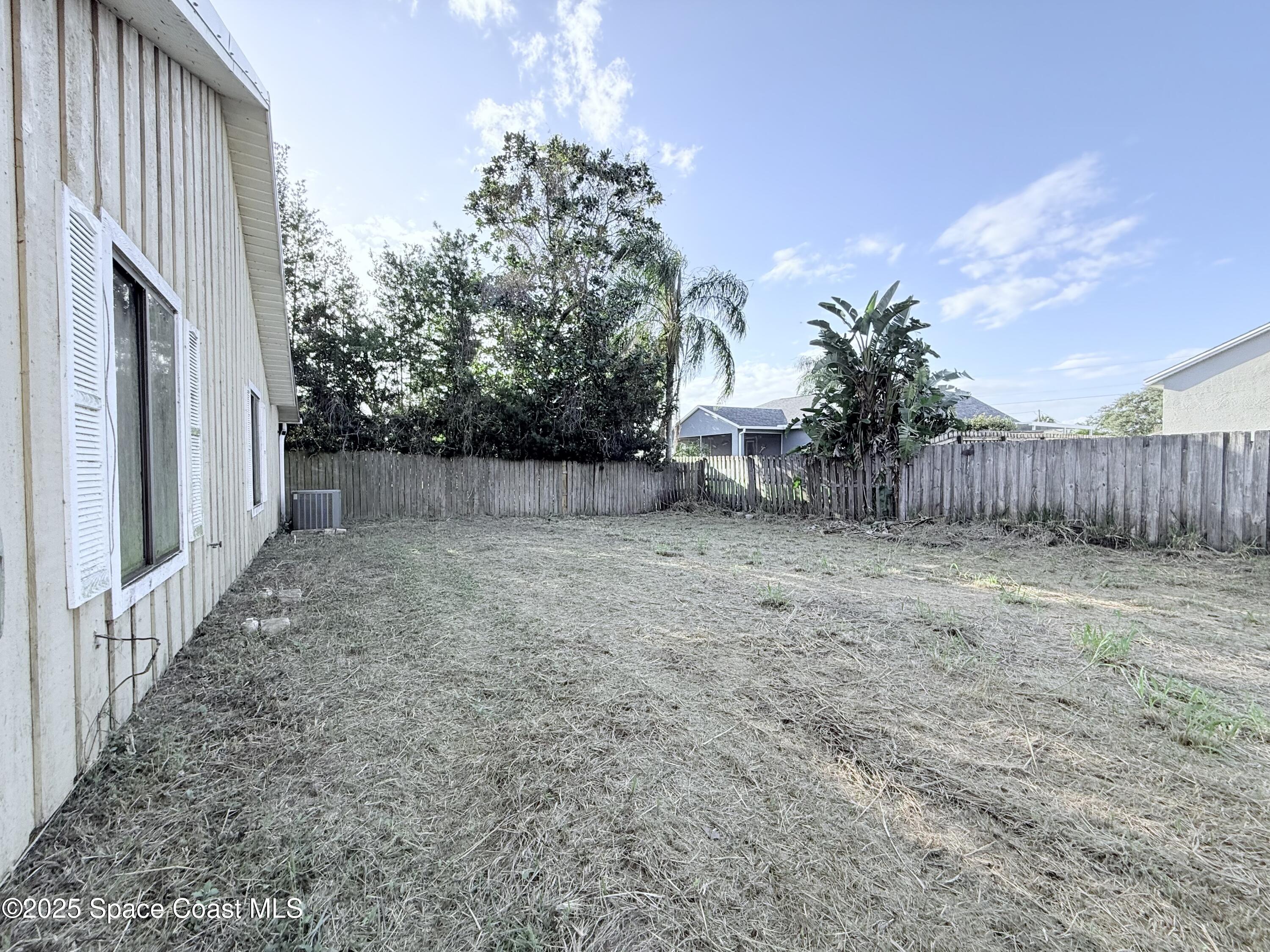 6180 Balboa Street Cocoa, FL 32927 - Photo 43 of 44 a view of a backyard with large trees and wooden fence