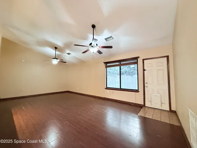 a view of an empty room with a window and wooden floor