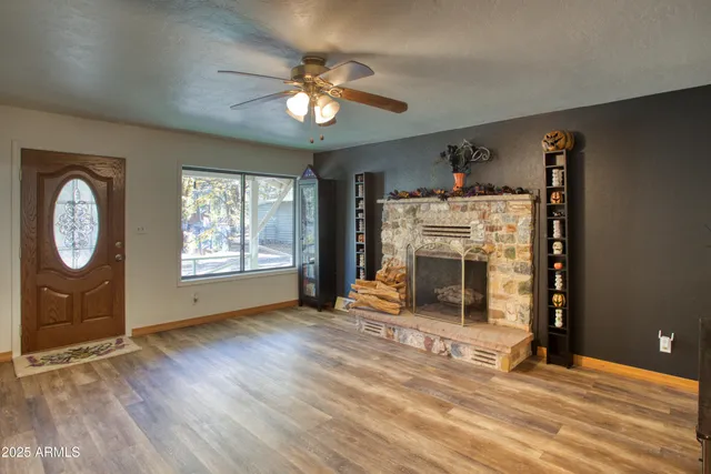an empty room with windows fireplace and fans