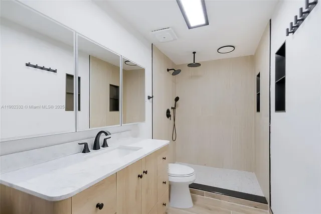 a bathroom with a sink a toilet a mirror and shower