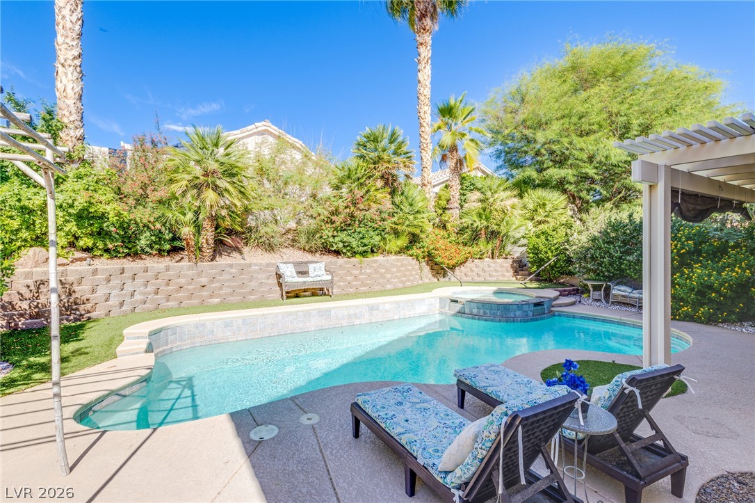 253 Camelback Ridge Avenue Henderson, NV 89012 - Photo 4 of 26 Mature palms and a tiered retaining wall frame the sparkling in-ground pool and integrated spa.