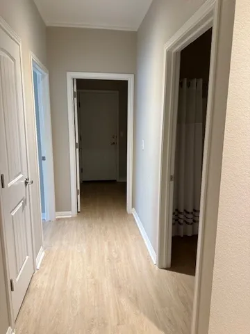 a view of a hallway with wooden floor and a bathroom