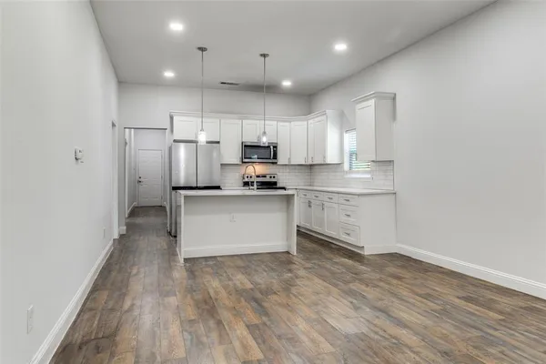 a kitchen with stainless steel appliances white cabinets and wooden floors