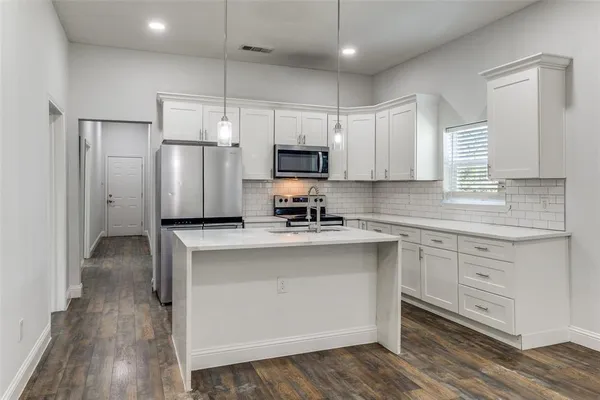a kitchen with refrigerator a stove a sink and white cabinets
