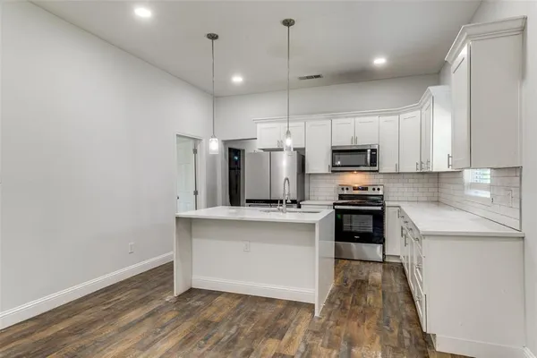 a kitchen with granite countertop a stove a sink and a refrigerator
