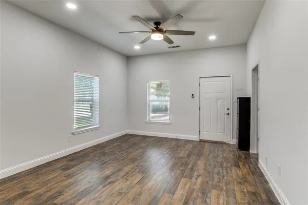 a view of an empty room with wooden floor and a window