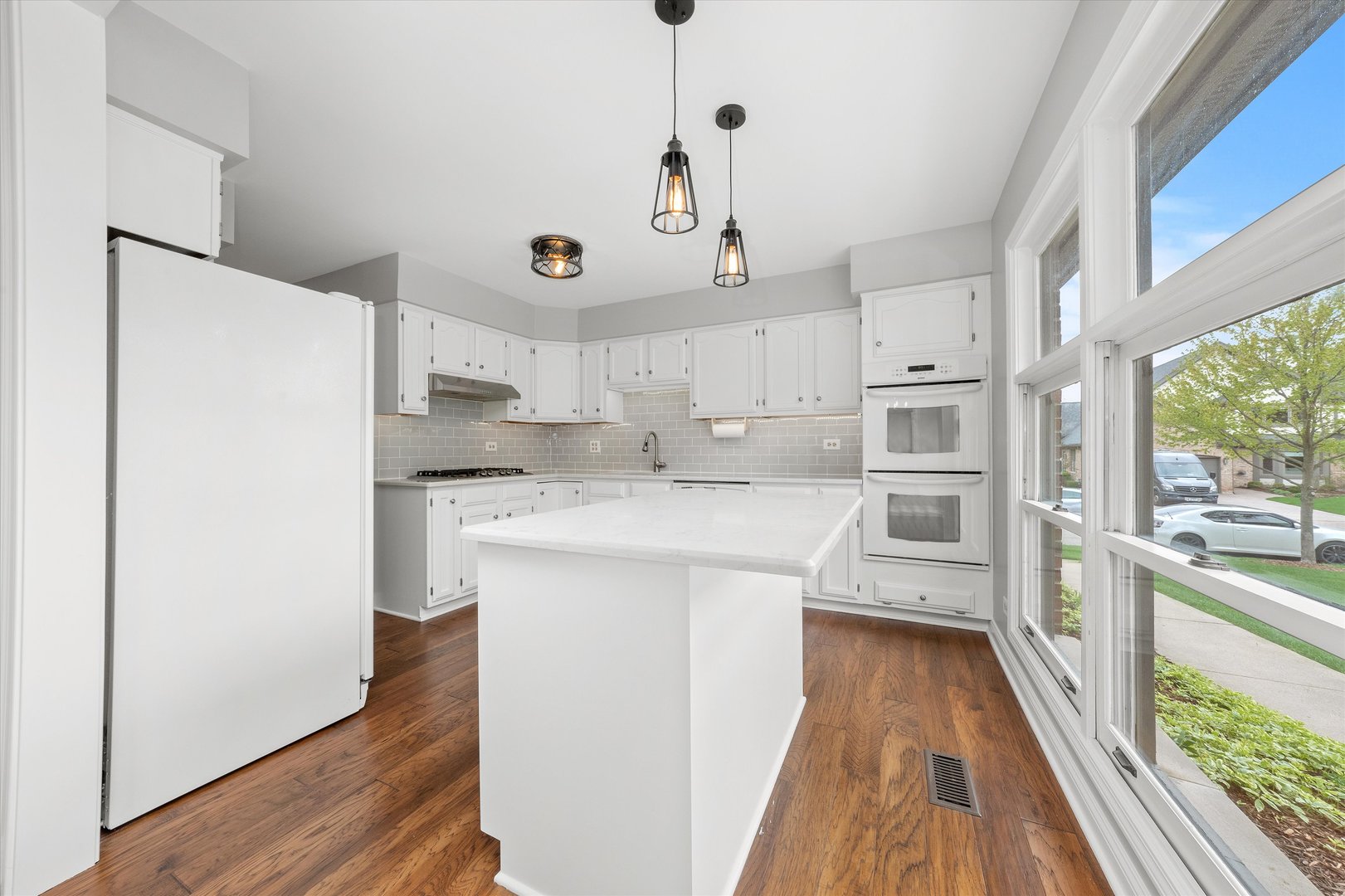 10620 Golf Road Orland Park, IL 60462 - Photo 15 of 42 a kitchen with kitchen island a sink a stove a refrigerator and white cabinets with wooden floor