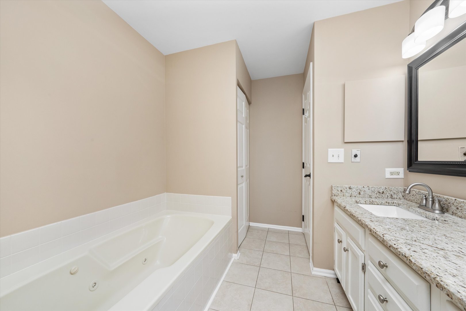 10620 Golf Road Orland Park, IL 60462 - Photo 26 of 42 a bathroom with a granite countertop sink a mirror and a bathtub