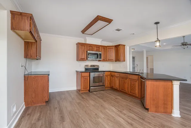 a large kitchen with stainless steel appliances granite countertop a stove a sink dishwasher and a oven with wooden floors