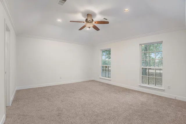 an empty room with windows and fan