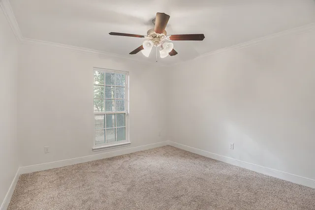 an empty room with windows and fan