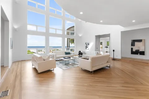 a living room with couches and kitchen view with wooden floor