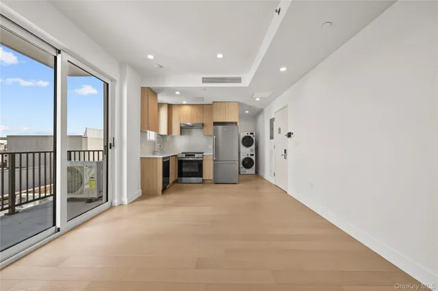 an empty room with stainless steel appliances wooden floor and windows