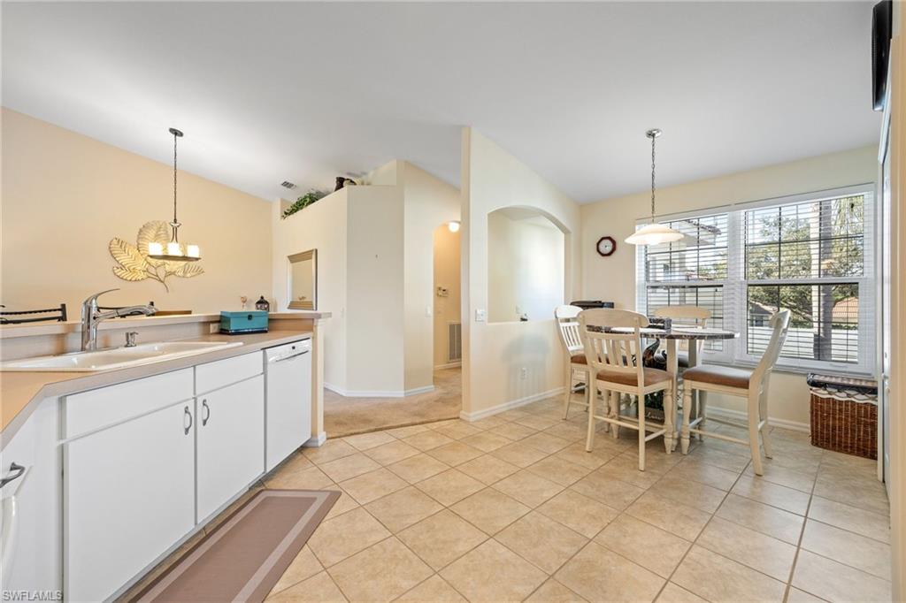 9209 Spring Run Boulevard, Unit 2003 Estero, FL 34135 - Photo 6 of 32 a kitchen with kitchen island granite countertop a sink dining table and chairs
