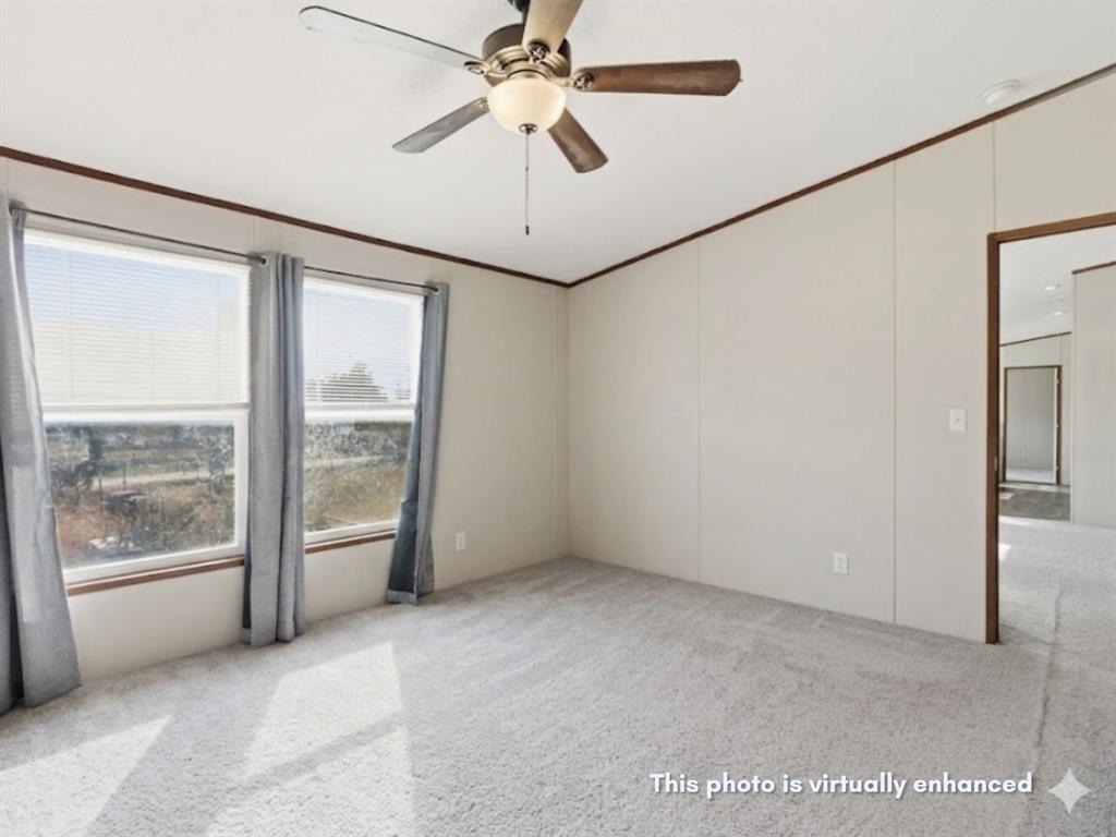 2722 Denver Road Sunset, TX 76270 - Photo 12 of 19 Carpeted room featuring two large windows, a ceiling fan with light fixture, and neutral wall paneling with dark trim