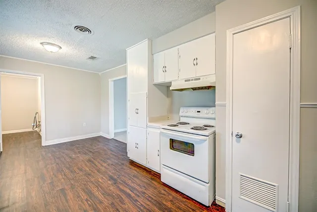 a kitchen with a stove cabinets and wooden floor