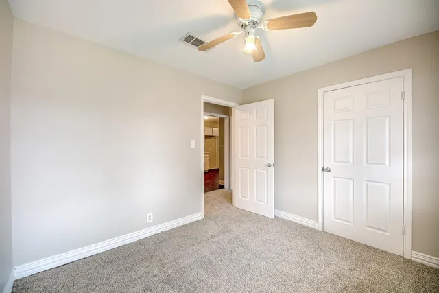 an empty room with a ceiling fan and a window