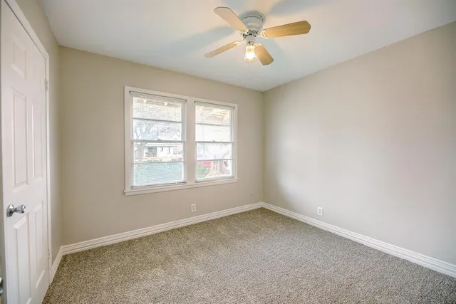 an empty room with a window and a fan