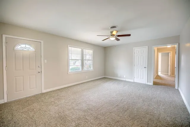 a view of an empty room with a ceiling fan and window