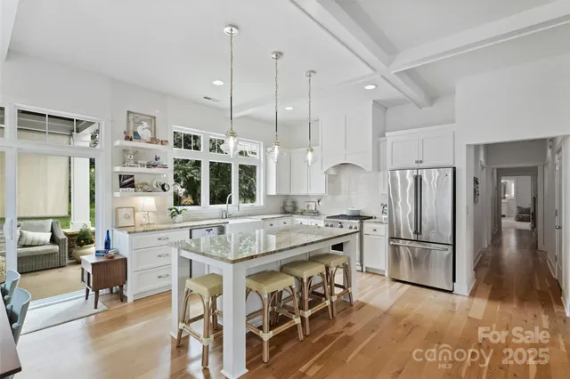 a kitchen with stainless steel appliances granite countertop a table chairs stove and refrigerator