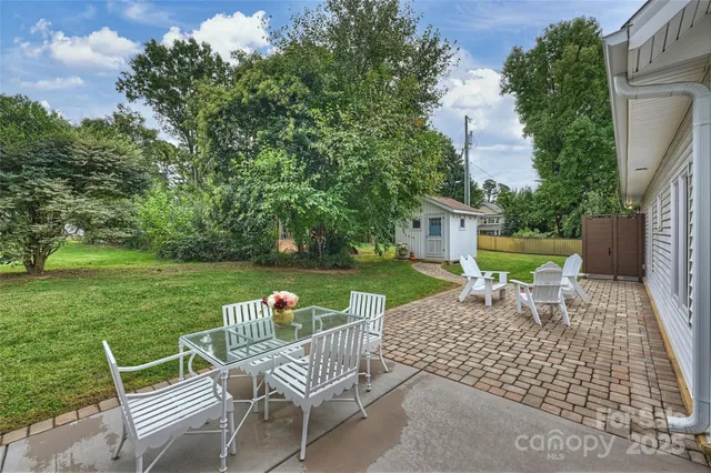 a view of a wooden chairs and table in backyard of the house