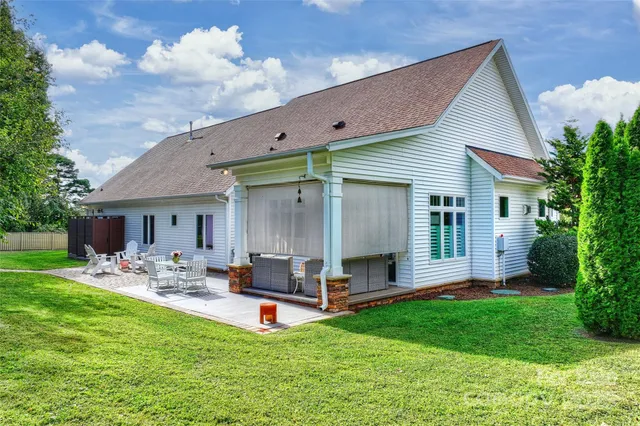a backyard of a house with table and chairs plants and large tree