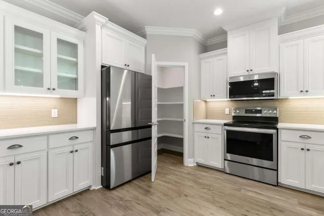 a kitchen with stainless steel appliances granite countertop a refrigerator a sink and white cabinets