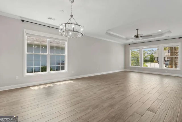 a view of a livingroom with a chandelier fan and wooden floor