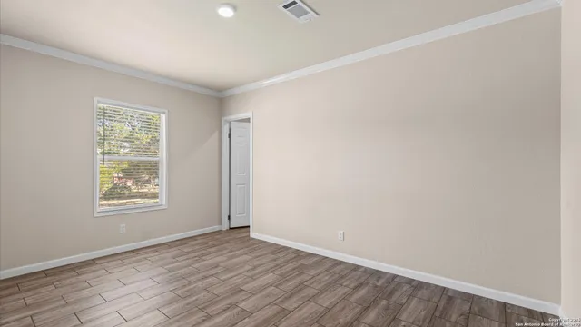 an empty room with wooden floor and windows