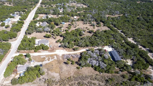 an aerial view of residential houses with outdoor space and trees all around