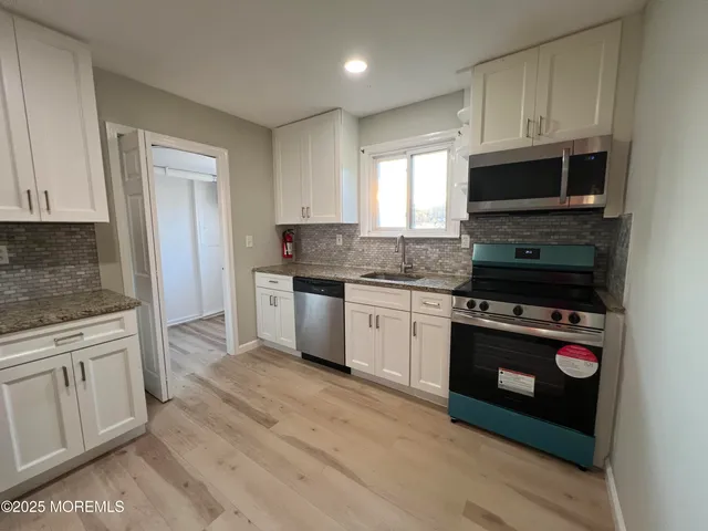 a kitchen with granite countertop a stove a sink and a microwave