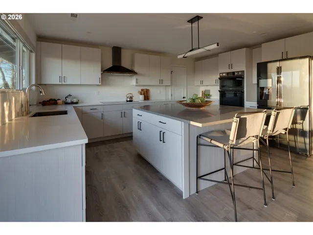 a kitchen with stainless steel appliances granite countertop a sink a stove a refrigerator cabinets and chairs