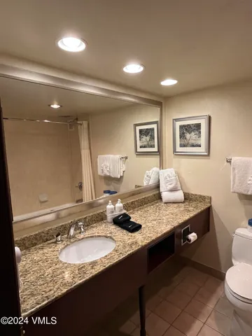 a bathroom with a granite countertop sink a toilet and a large mirror